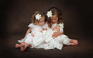 two girl wearing white shirts holding baby