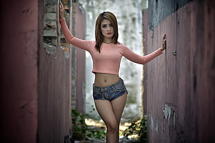 woman wearing pink long-sleeved crop top and faded denim short shorts