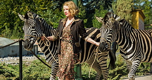 woman wearing blazer holding two zebras