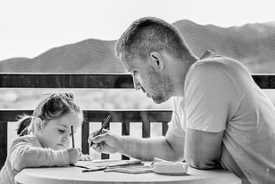 grayscale of a man tutoring his daughter on a table scenery HD wallpaper