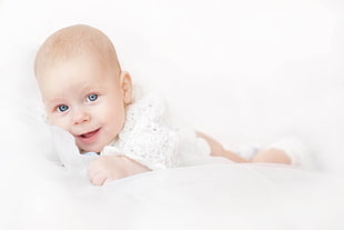 baby's smiling and crawling on white mattress