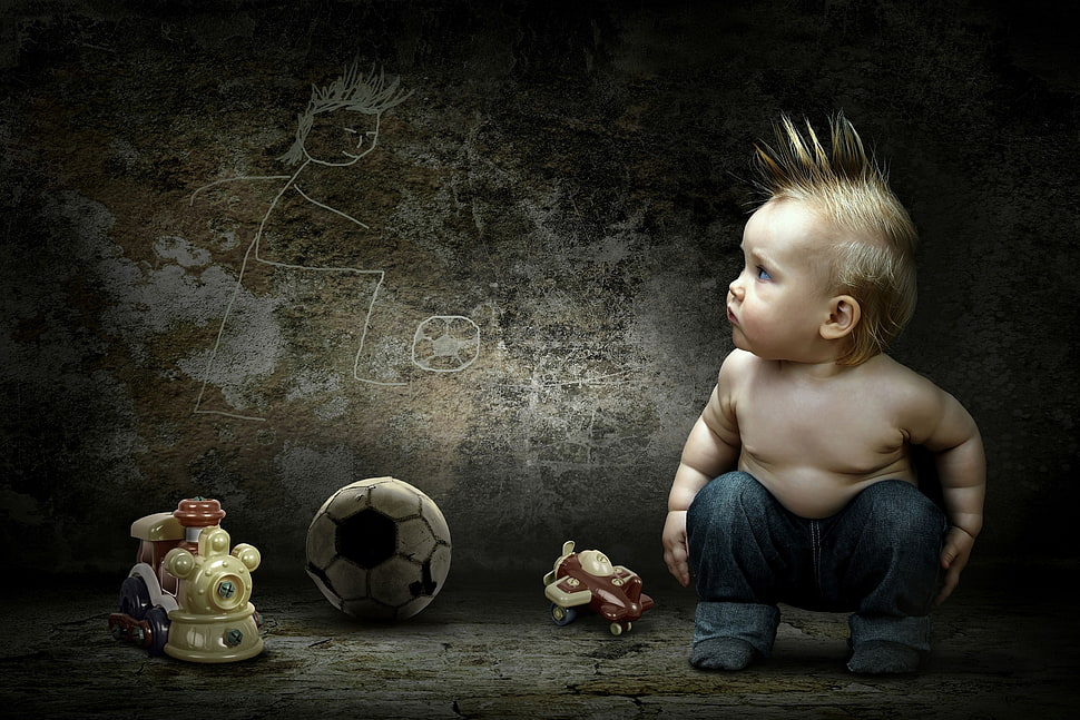 photography of boy with blue jeans sitting near white and black soccer ball HD wallpaper