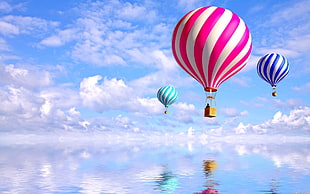 three hot air balloon above wide body of water