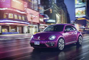 purple Volkswagen New Beetle on road passing across building timelapse photography