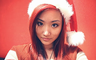 woman wearing santa hat with red hair and red background