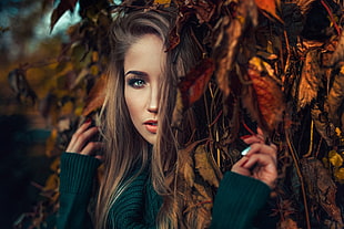 woman wearing green sweater hiding on brown leaf tree