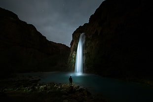 silhouette of human standing in front of waterfalls