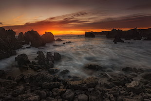 photo of rocks formation on seashore during sunset