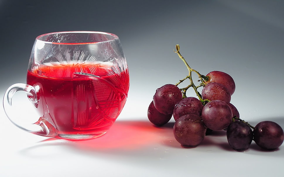 clear glass cup beside grapes on white surface HD wallpaper