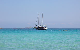 black sail boat on blue body of water during daytime