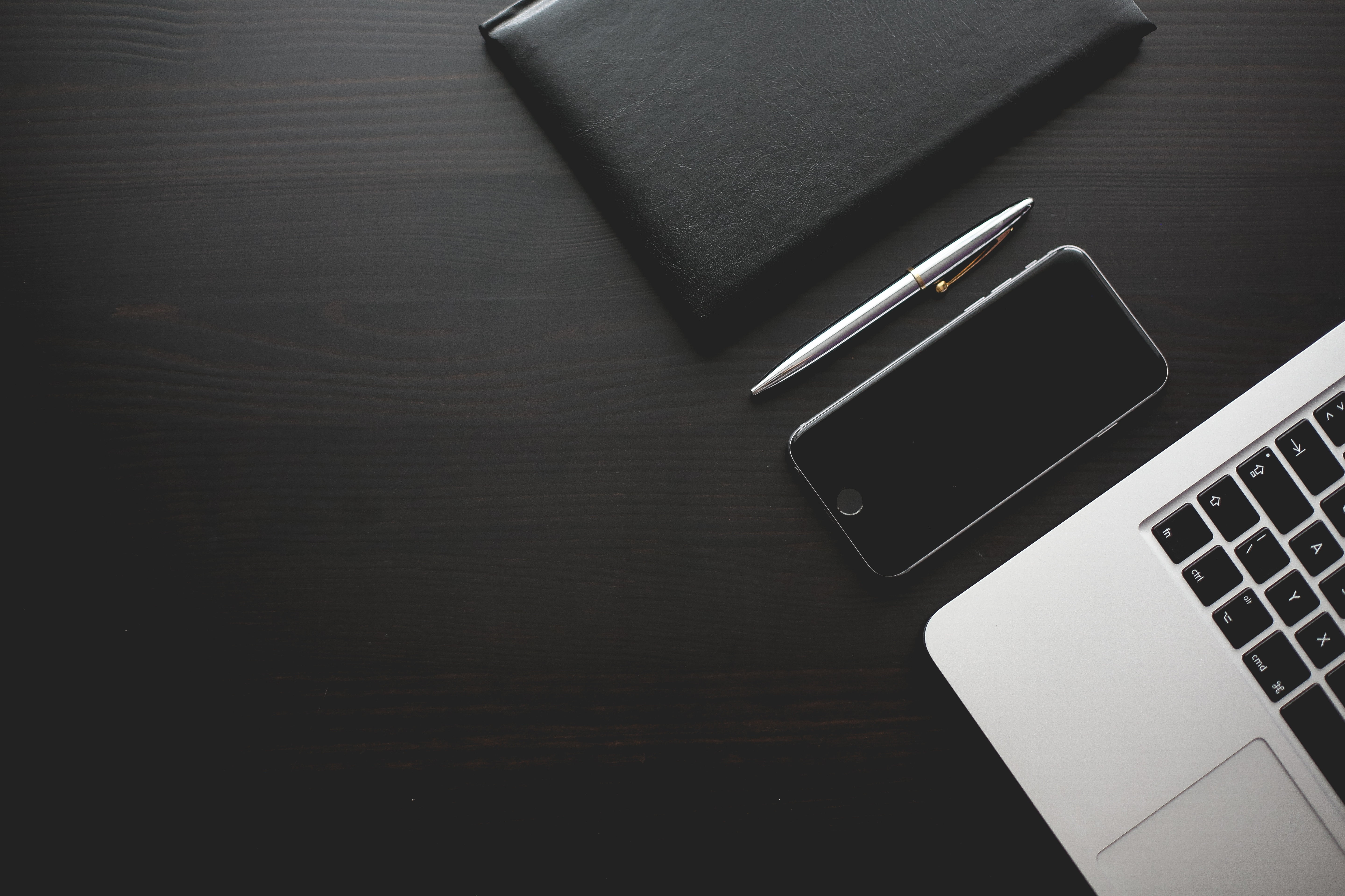 space gray iPhone 6 near macbook beside silver pen and black leather binder