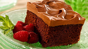 chocolate cake near strawberries on glass saucer