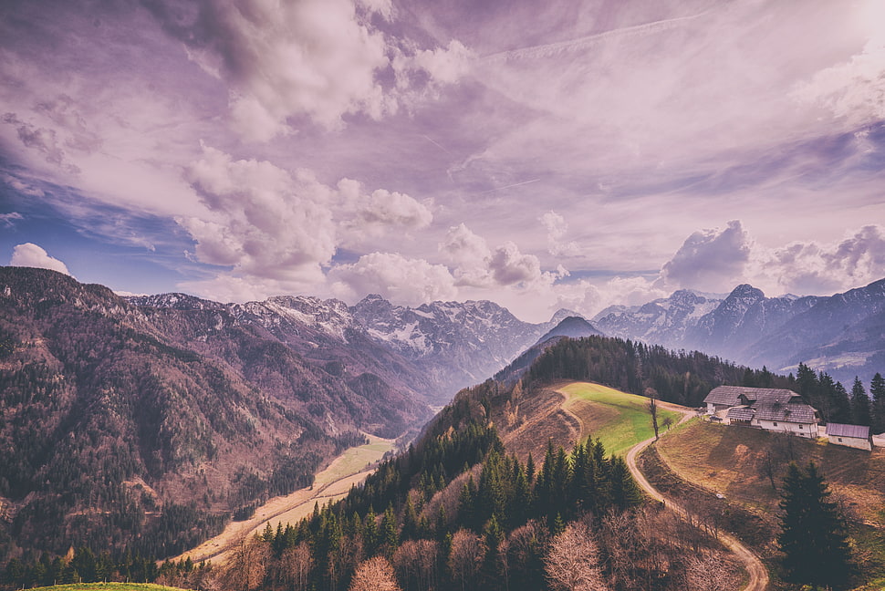 green trees on mountain tops under cloudy sky HD wallpaper