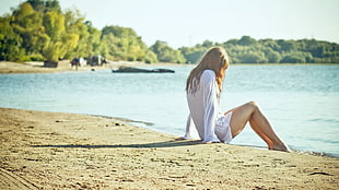 woman in white dress sitting on seashore