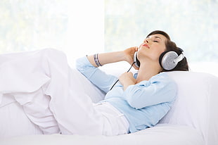 woman in blue dress shirt with white pants wearing headphones