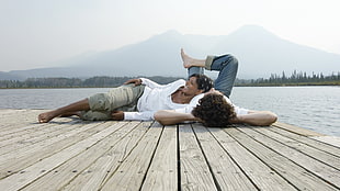 couple wearing white dress shirts lying on brown wooden dock sea floor during daytime