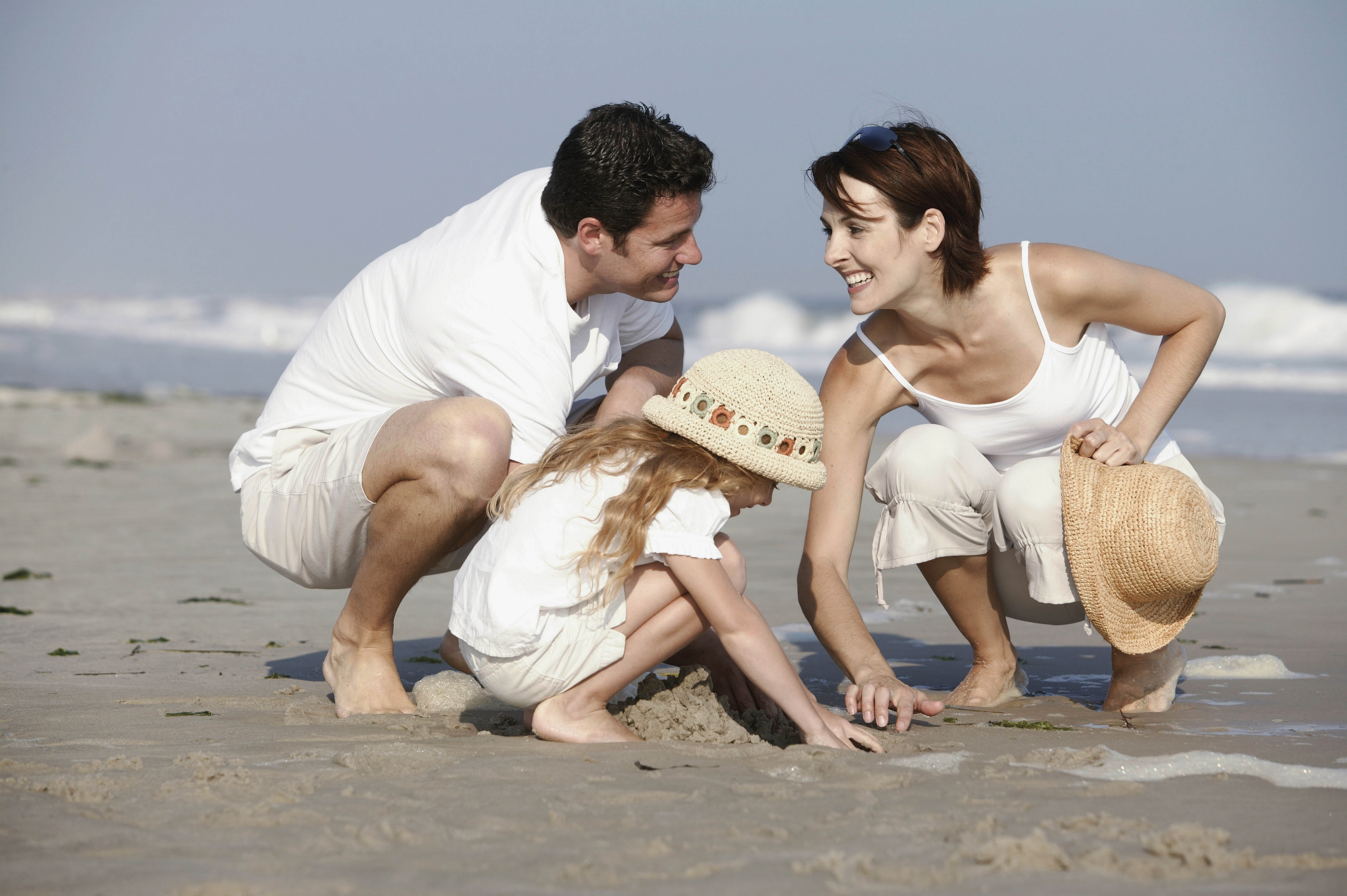 photo of man , woman and child playing sand at sea shore while smiling HD w...