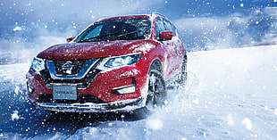 red Nissan five door hatchback on snowfield during daytime close-up photography
