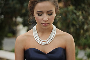 photo of woman with black sweetheart dress wearing a white beaded necklace