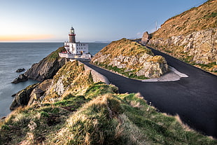 white and brown light house on hills during day time, baily lighthouse, dublin, ireland