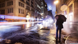 timelapse photo of woman holding brown umbrella near street during nighttime