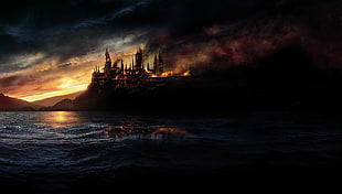 burning castle near body of water and mountain