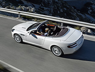 woman driving a white Aston Martin coupe convertible during daytime
