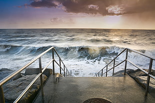 stairs with stainless steel railings in front of waves