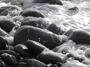 timelapse photo of splashing water on black stones
