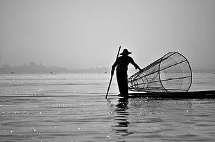 silhouette of man on boat on body of water during daytime