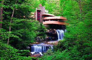 brown building beside of river with waterfalls