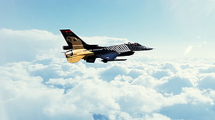 black and yellow jet plane above white clouds