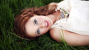 woman wearing white top laying on green grass