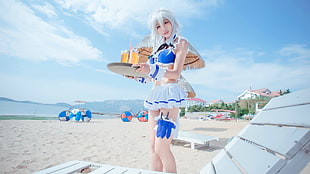 photo of girl wearing blue and white cosplay outfit in seashore during day time