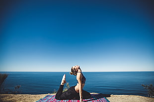 woman in black sports bra doing yoga near  body of water