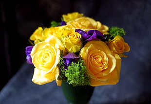 selective focus photography of yellow, purple, and green floral arrangement on green vase