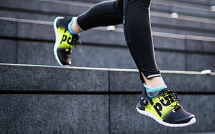 person wearing pair of athletic shoes walking down on concrete stairs closeup photography