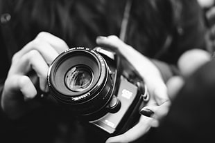 gray-scale photography of person holding DSLR camera