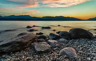 brown rocks bear body of water during sunset HD wallpaper