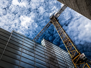 yellow steel crane beside of glass building HD wallpaper