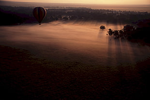 hot air balloon passing by body of water