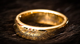 gold-colored ring on brown wooden surface
