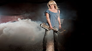 woman in blue shirt holding saxophone