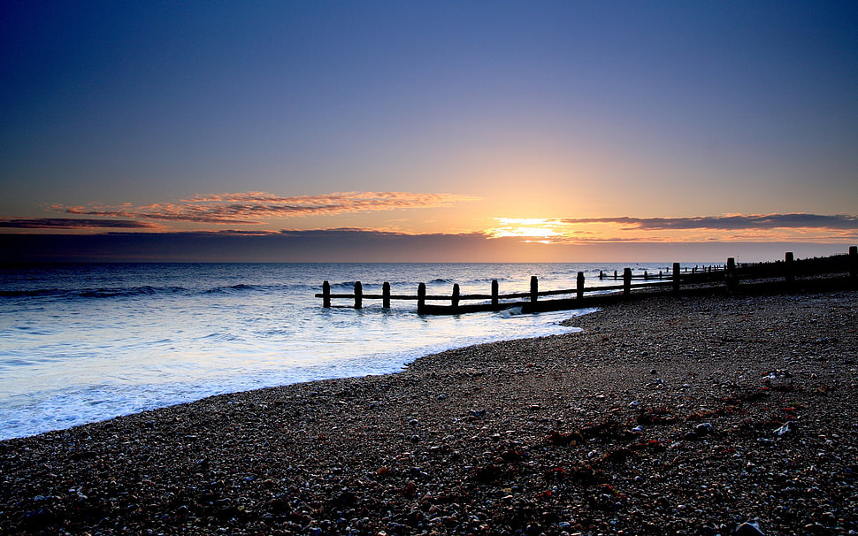 brown dock beside black sand at sunset HD wallpaper