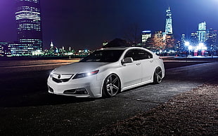 white Acura TL parked on roadway overlooking highrise buildings during night time