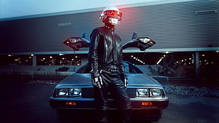 man in black leather jacket and pants standing in front of silver car