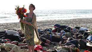 woman holding flower bouquet standing at the center of people lying down