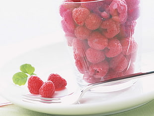 Raspberries on spoon and in clear glass container