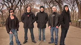 five man wearing black jackets standing on pathway