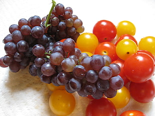 bunch of tomato and grapes on white surface